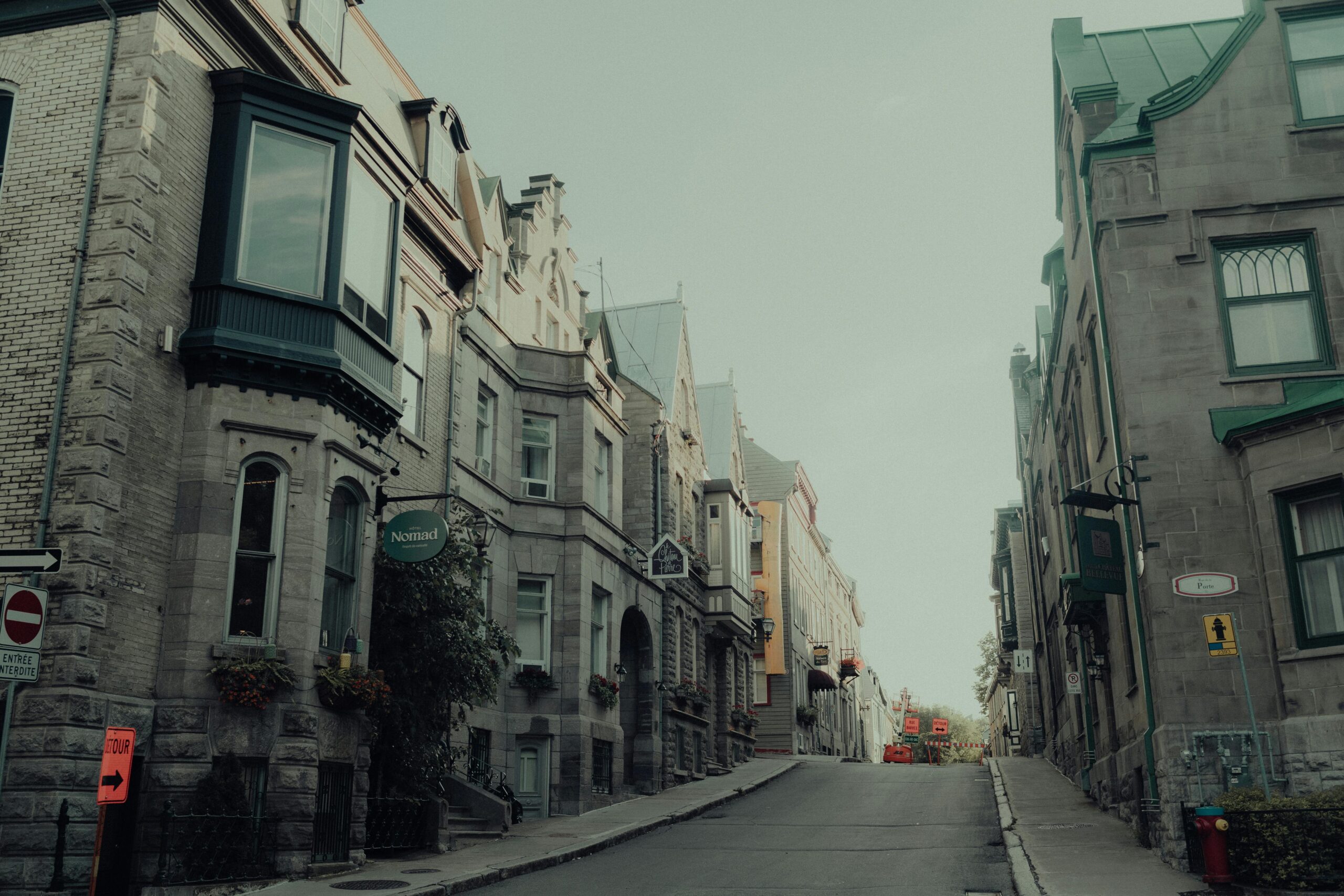 Historic cityscape featuring cobblestone streets and Victorian-era brick buildings illuminated at dusk.