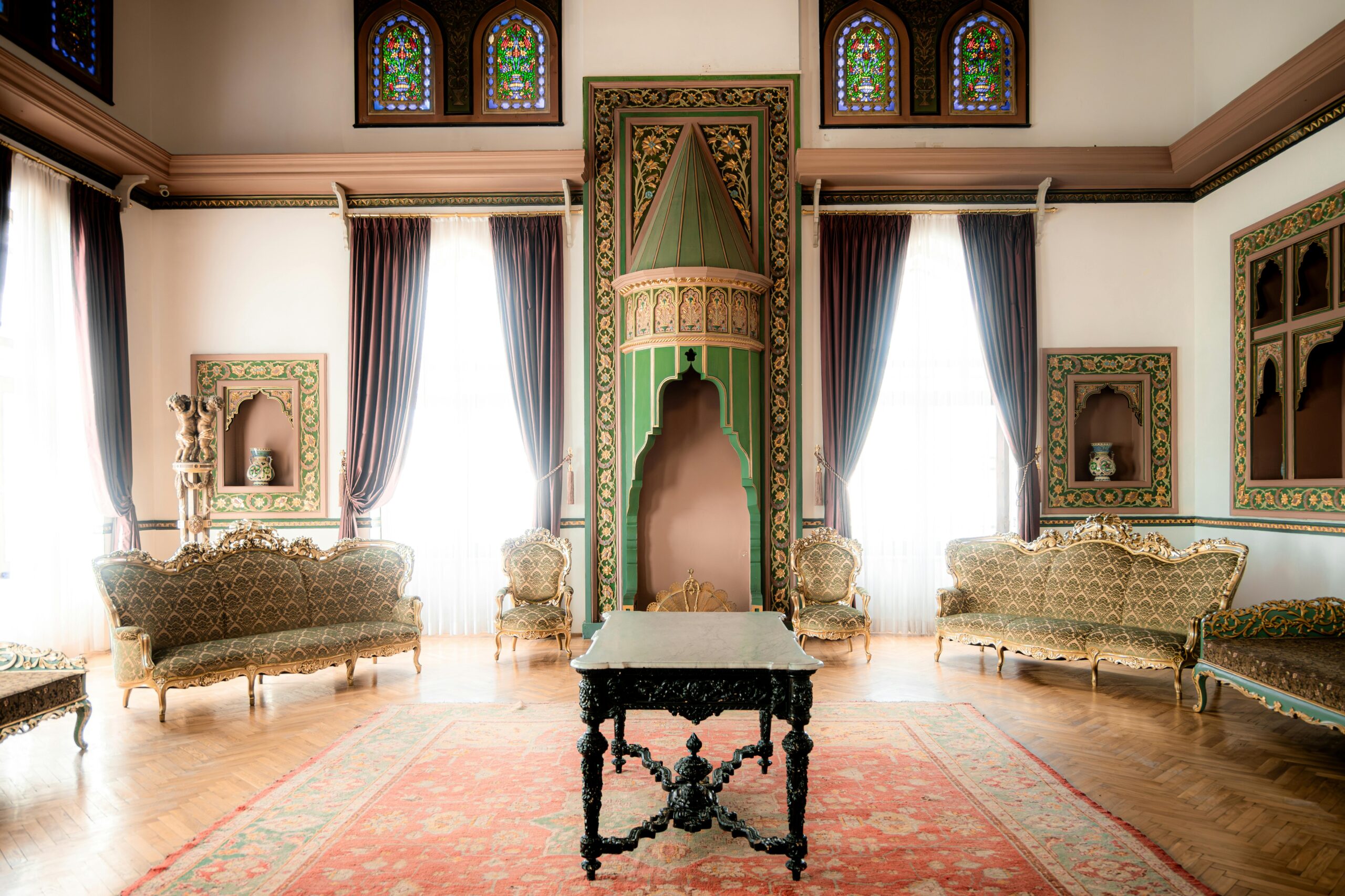 A cozy living room with plush velvet chairs, an ornate chandelier, and antique bookshelves.