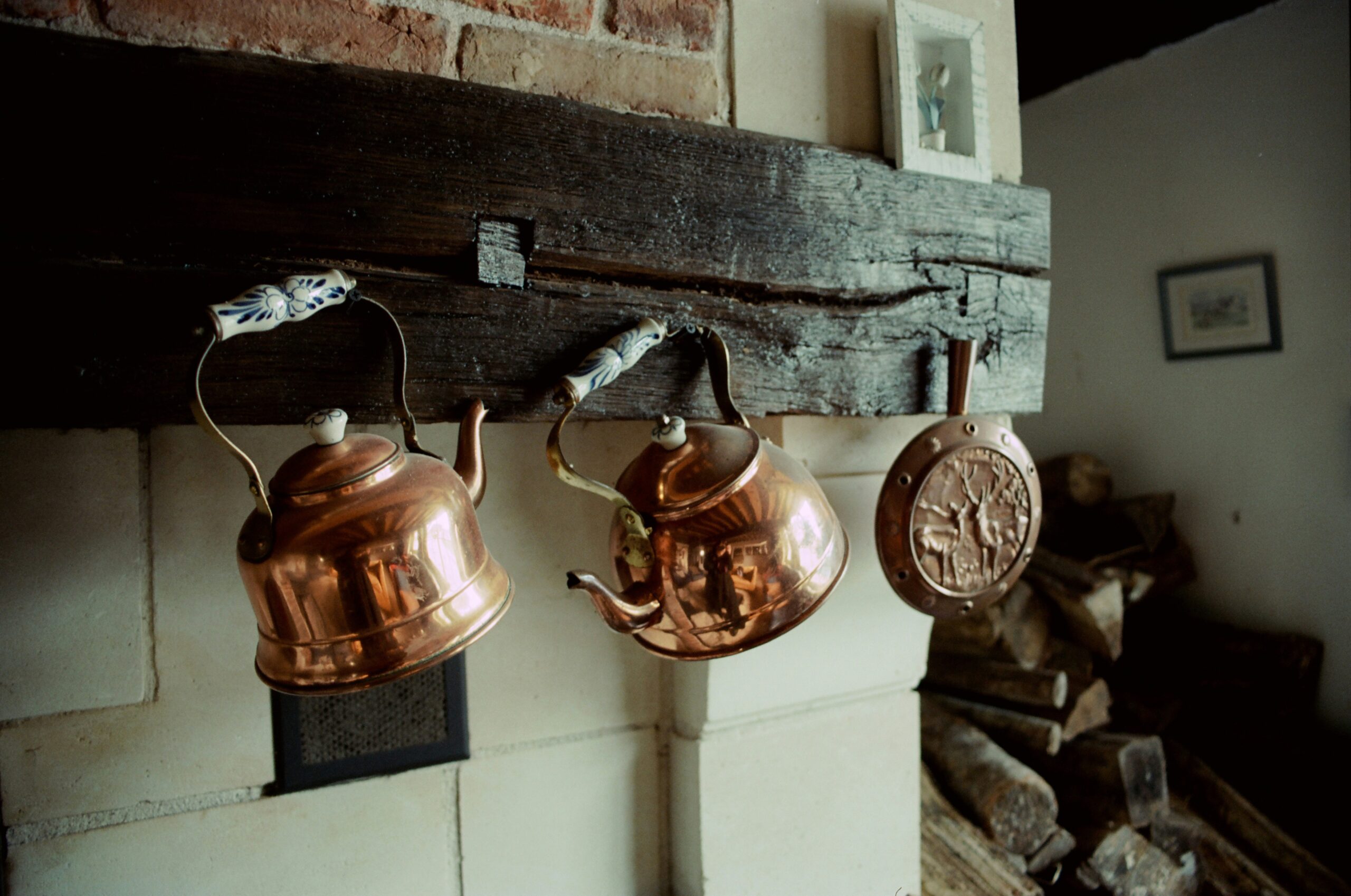 A vintage kitchen in a historic villa with copper pots hanging above a stone hearth