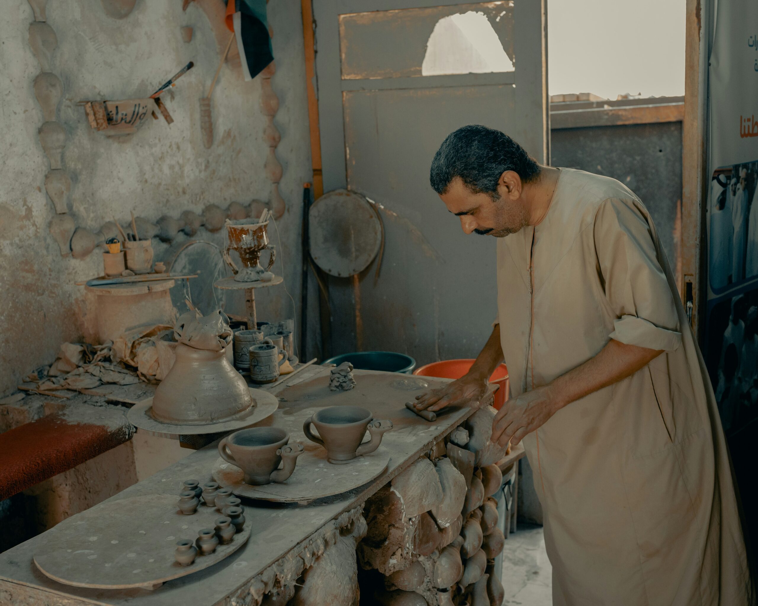 An artisan teaching pottery in a rustic workshop