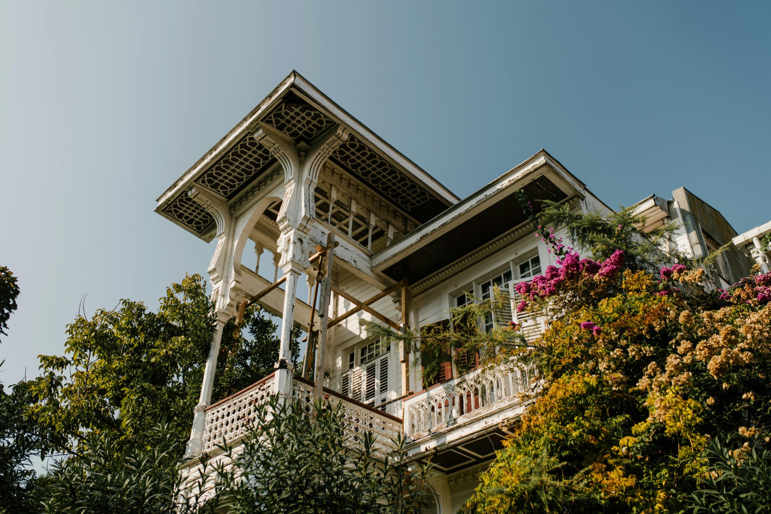 An exterior shot of a charming historic home surrounded by lush gardens.