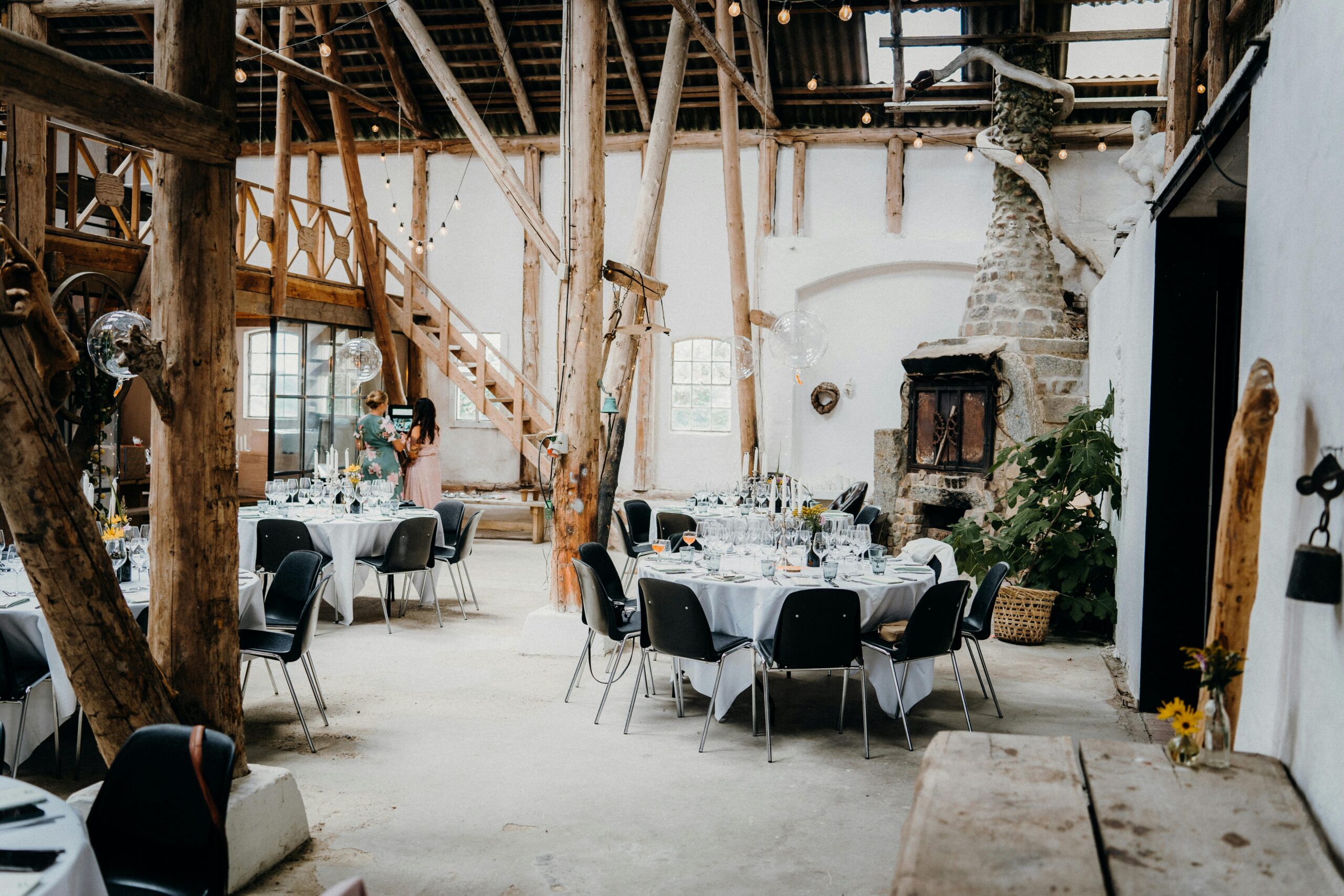 Cozy interior of a restored log cabin featuring exposed beams, a stone fireplace, and vintage furnishings