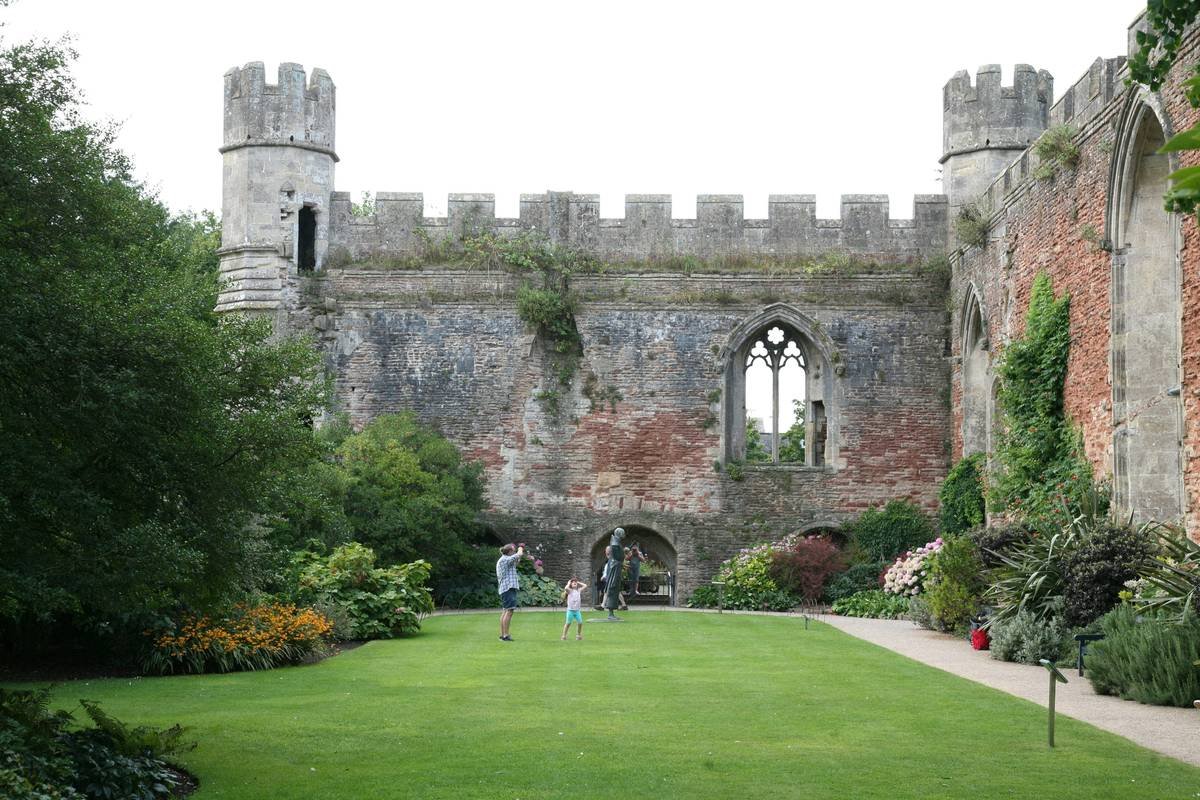 A picturesque view of a sunlit castle surrounded by lush greenery.