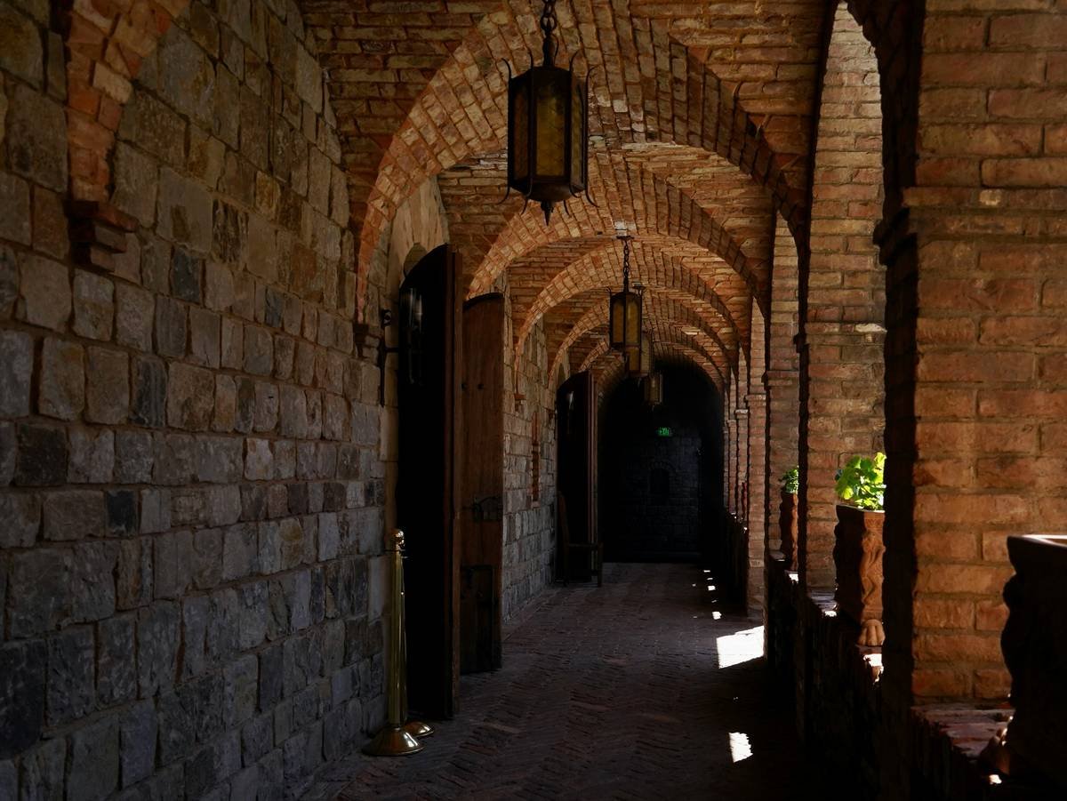 A visitor holding a lit torch inside a dimly lit medieval dungeon.