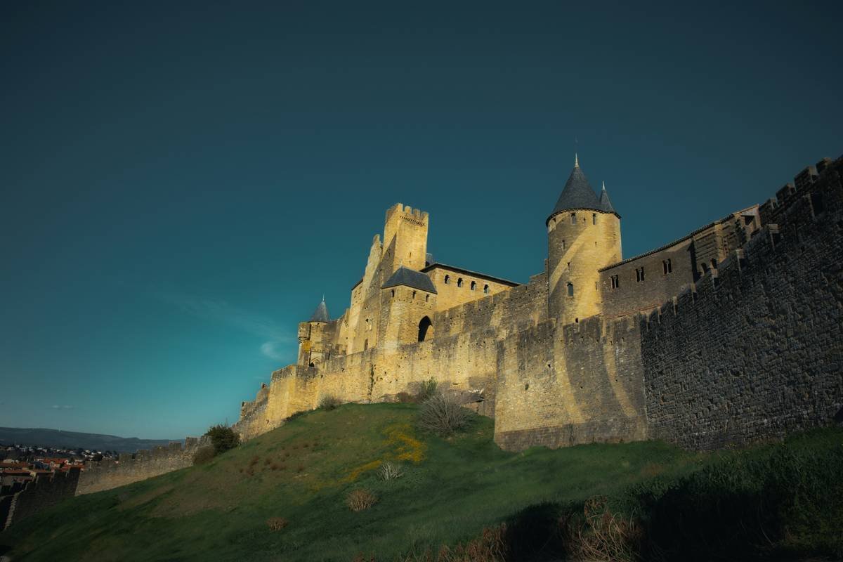 Guests enjoying a grand feast indoors under chandeliers hanging from high vaulted ceilings.