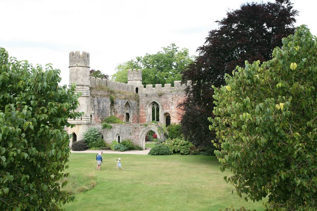 Participants learning falconry techniques with birds of prey against a castle backdrop.