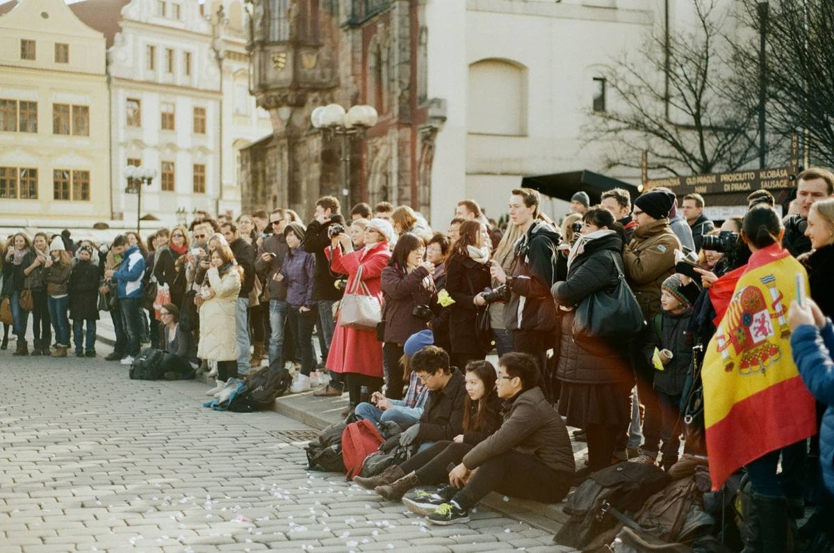 People dressed in colonial attire gathered around a town square fountain.