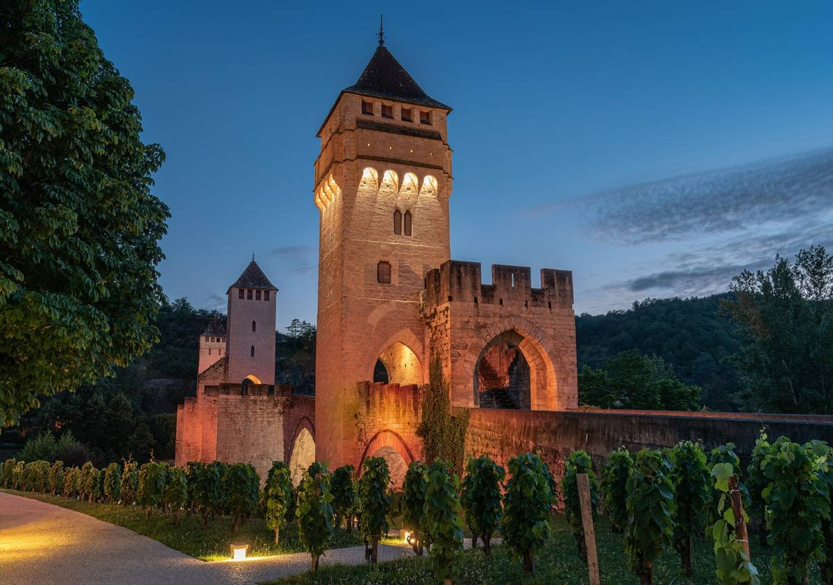 A medieval banquet setup featuring long wooden tables adorned with candles inside a historic castle.