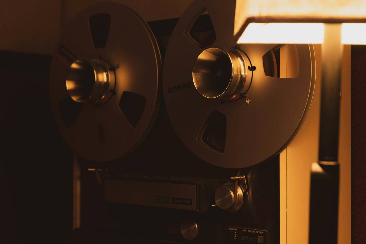 A small portable projector placed on a table projecting onto a white wall