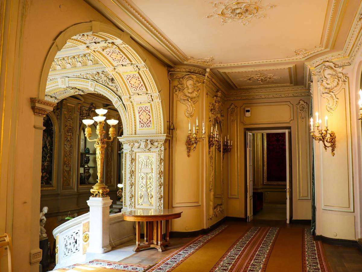 An opulent staircase inside a grand mansion decorated in early 20th-century style