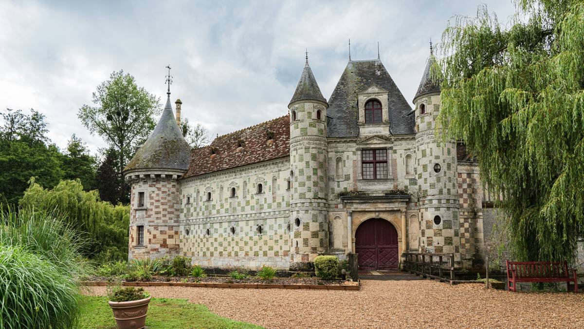 A romantic view of a lit-up heritage chateau at dusk.