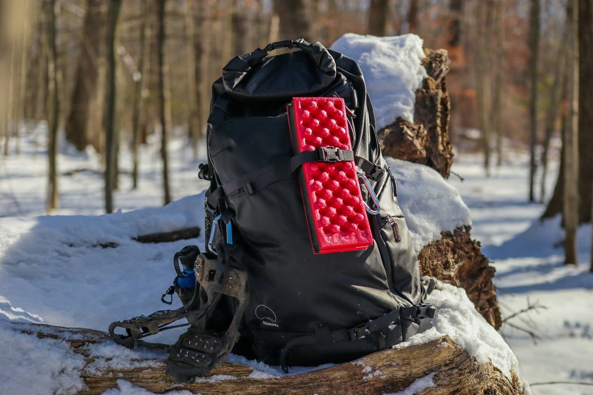 a backpack sitting on top of a log in the snow