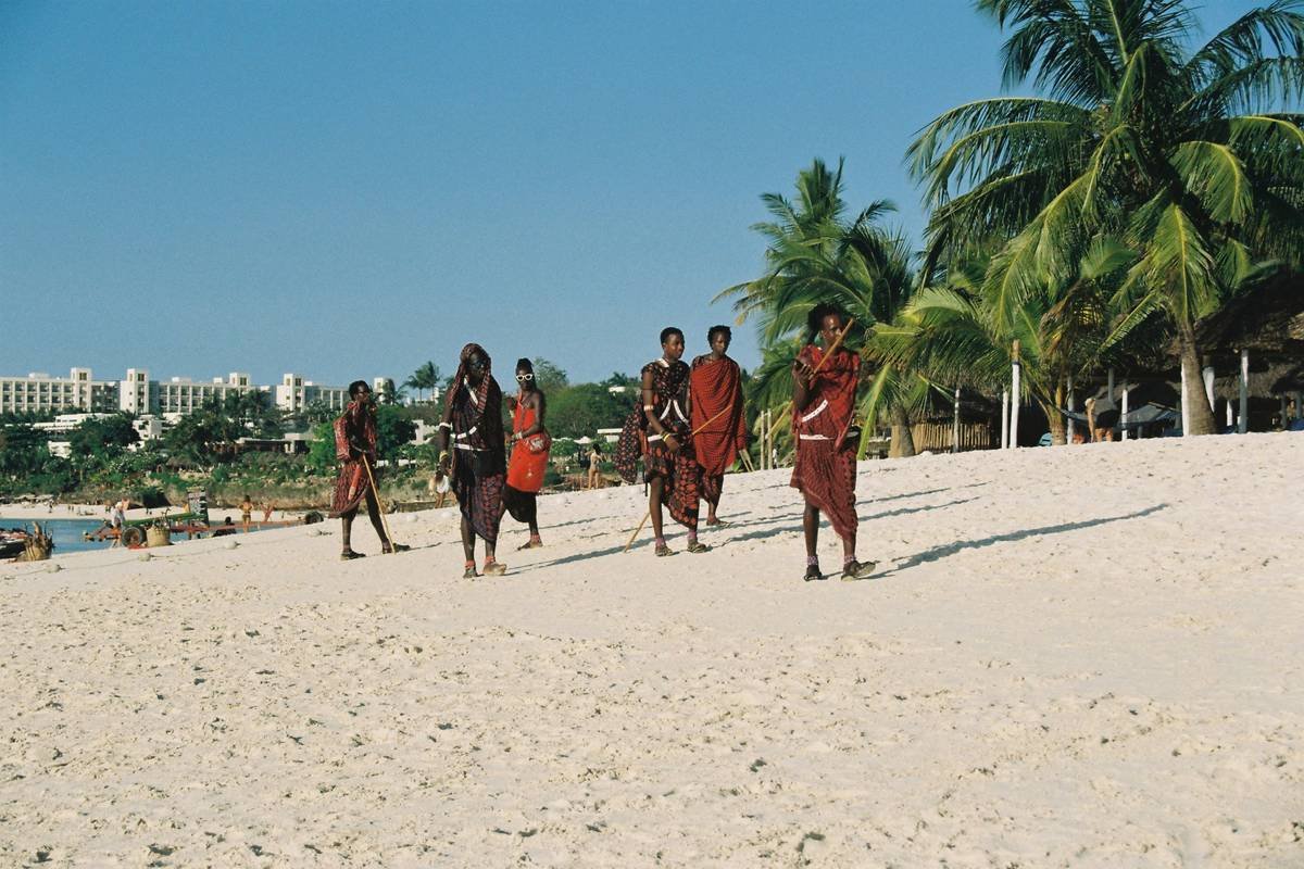 A candid moment captured on film, Maasai people strolling on east African shore in their traditional attire.