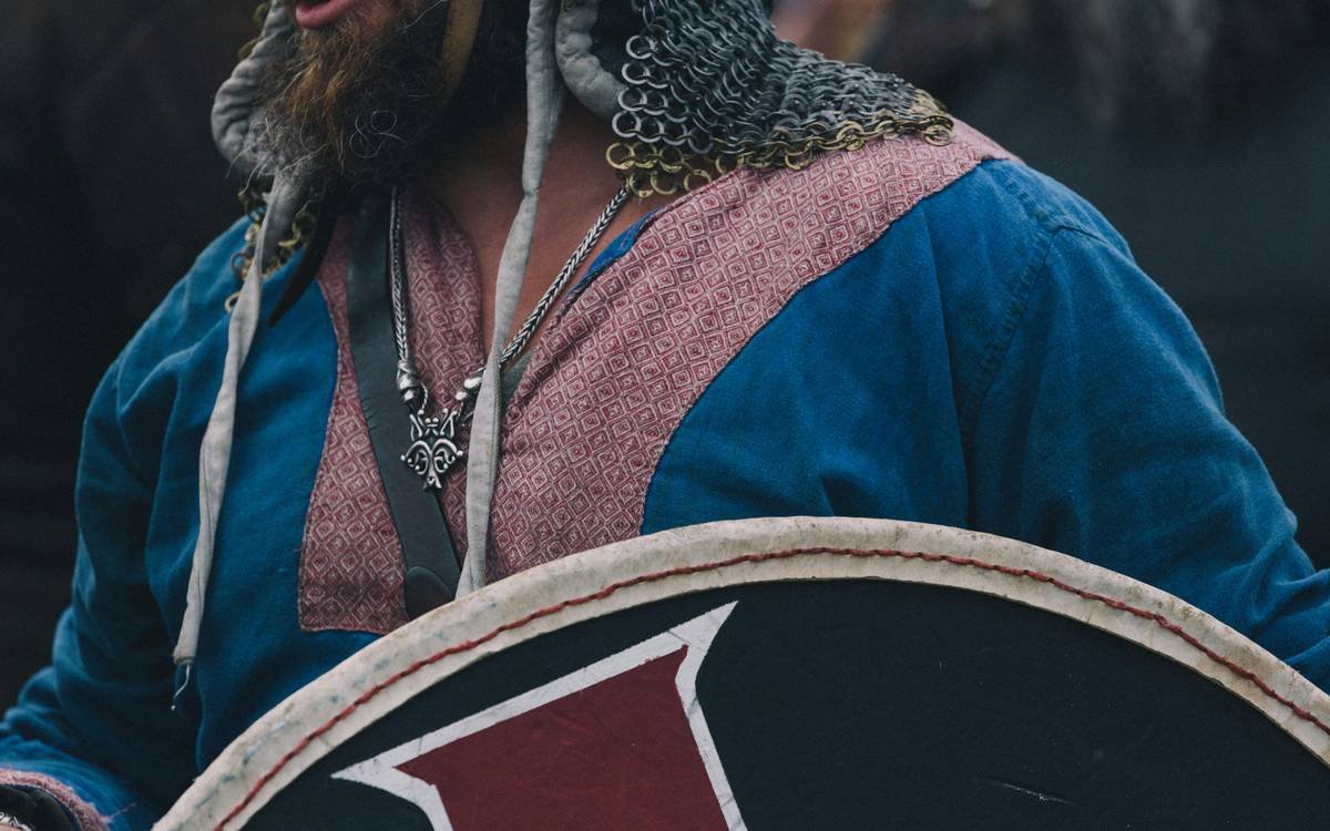 A viking warrior in chainmail and tunic holding a shield.